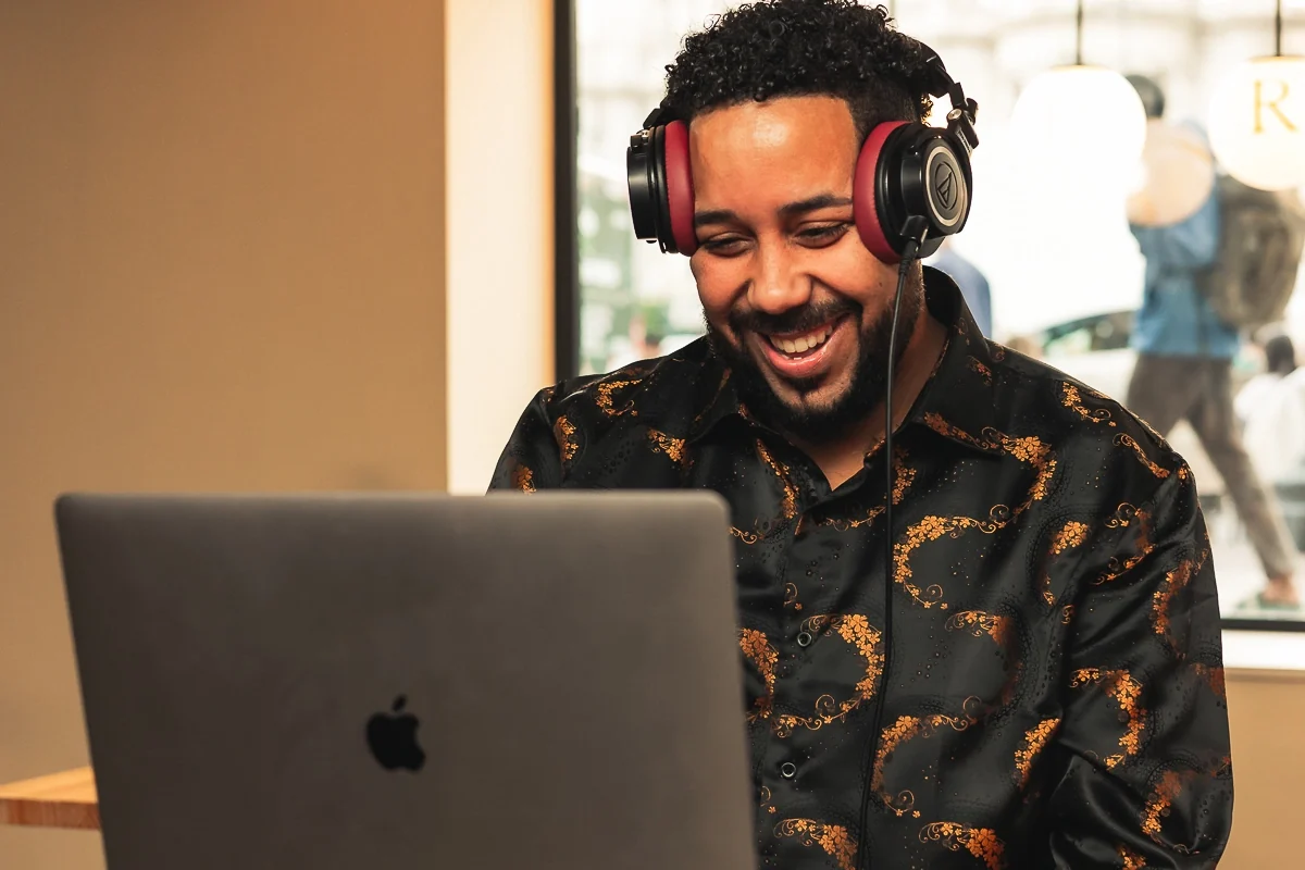 DJ KnowaY wearing headphones and performing behind his laptop.