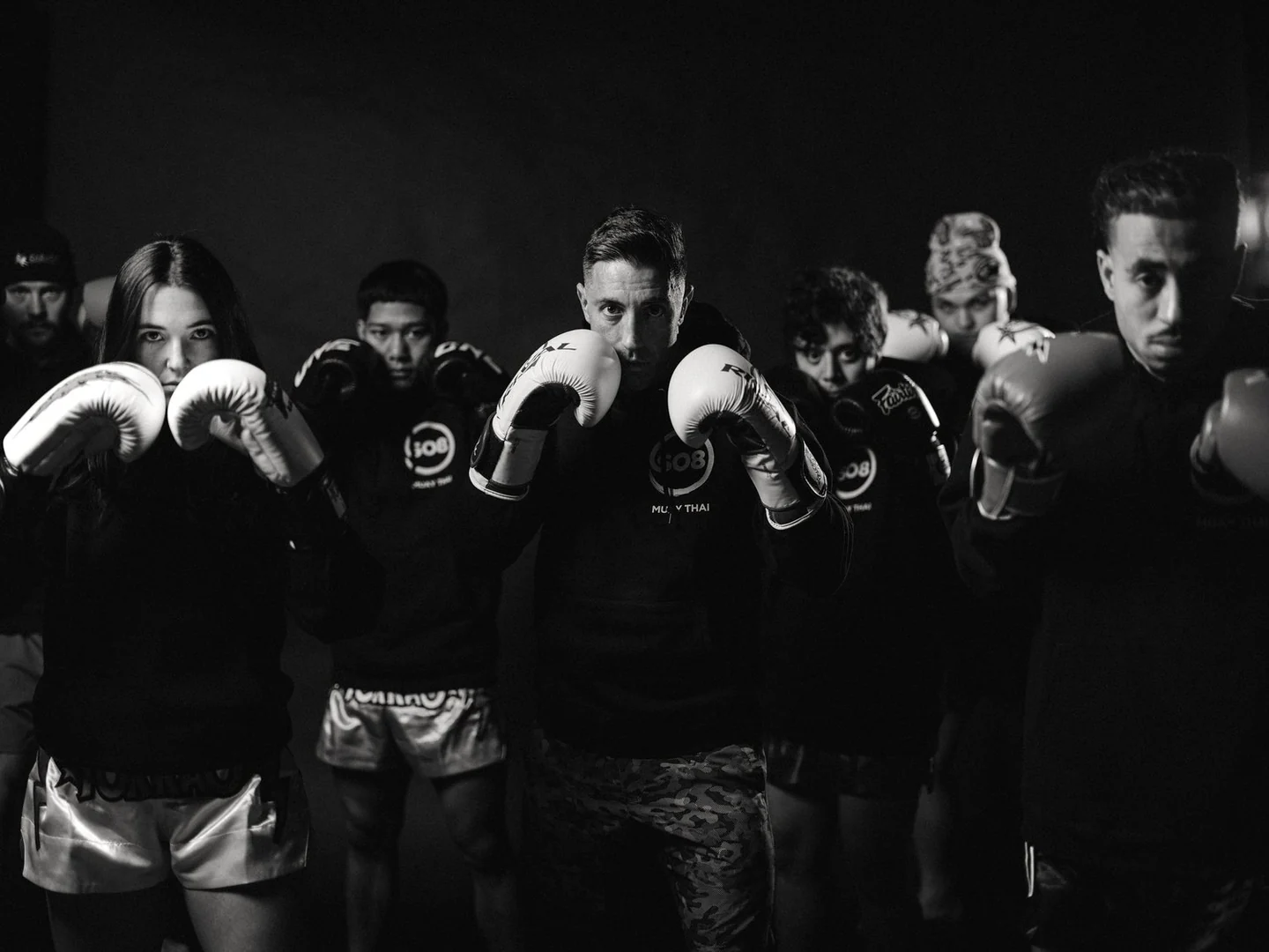 SO8 Muay Thai members posed with boxing gloves in their gym.